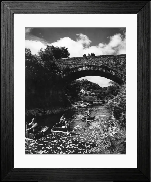Framed Print : Passers-by stop on Cenarth Bridge to look at the coracle men plying their craft down Framed Print : Passers-by stop on Cenarth Bridge to look at the coracle men plying their craft down