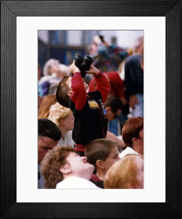 Framed Print : A young spectator looks through a pair of binoculars at an air display at the Sunderland