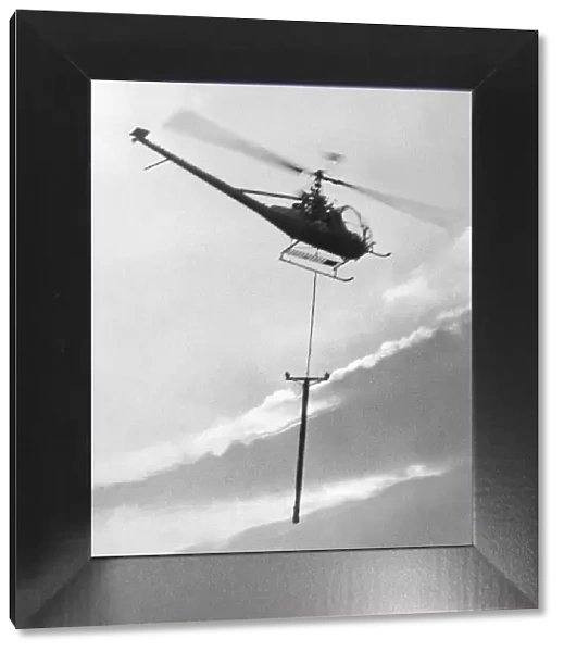 A Hiller 12E helicopter carries a telegraph pole across Grouse Moor at Kings Law