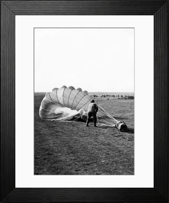 Framed Print : A paratrooper hauling in the parachute attached to a container which has been dropped Framed Print : A paratrooper hauling in the parachute attached to a container which has been dropped