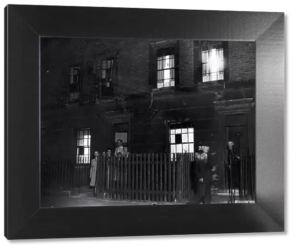 A family posing outside their home in Cab; e Street, Mile End London during a dim-out