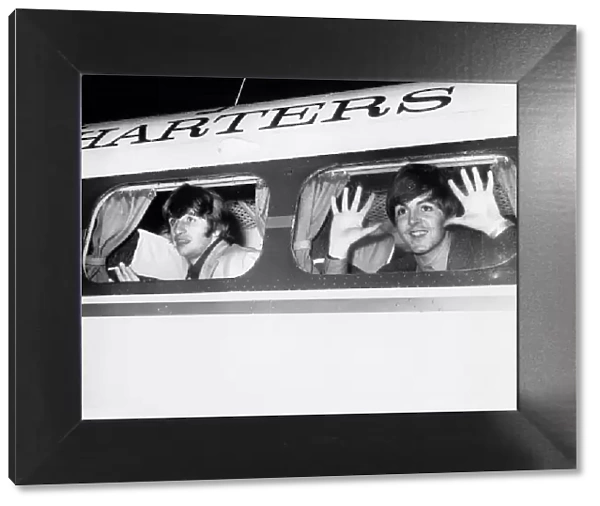 Beatle members Ringo Starr (left) and Paul McCartney look out of the window of plane at