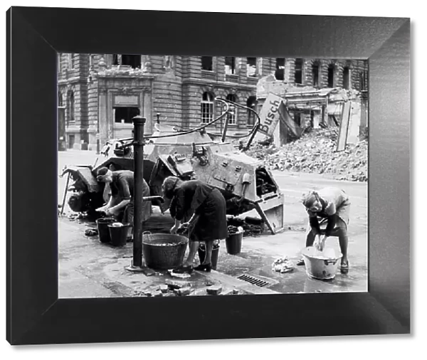 German women doing their washing in cold water in a street beside a knocked out German