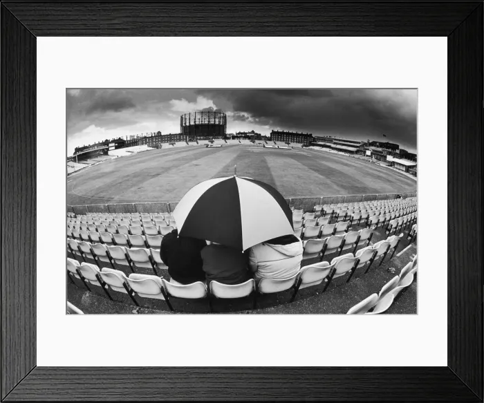 Framed Print : Spectators sit out showers underneath an umbrella as they wait for Pakistan Framed Print : Spectators sit out showers underneath an umbrella as they wait for Pakistan