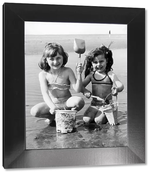 Wish you were here! Sharon-Anne Taney, left, and Maria Grant build a sand castle in