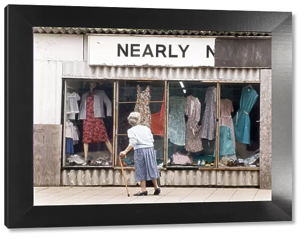 An elderly woman pauses to look at the World War Two prefab shop on the corner of