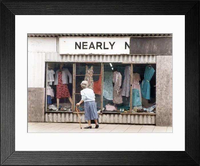 Framed Print : An elderly woman pauses to look at the World War Two prefab shop on the corner of Framed Print : An elderly woman pauses to look at the World War Two prefab shop on the corner of