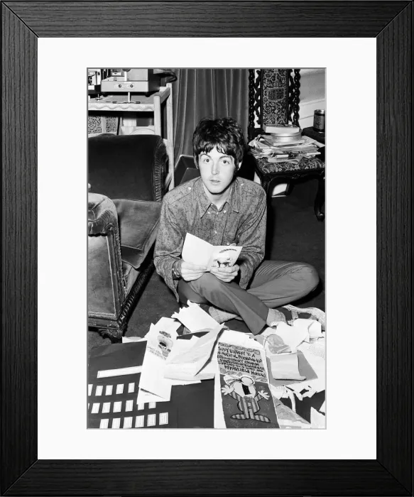 Framed Print : Paul McCartney of The Beatles sitting on the floor cross legged as he opens up birthday