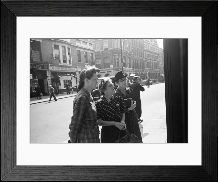 Framed Print : Shoppers looking for a bargain read the small ads outside a Earls Court News Agents Framed Print : Shoppers looking for a bargain read the small ads outside a Earls Court News Agents