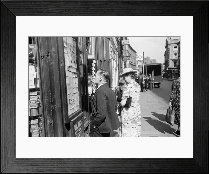Framed Print : Shoppers looking for a bargain read the small ads outside a Earls Court News Agents Framed Print : Shoppers looking for a bargain read the small ads outside a Earls Court News Agents