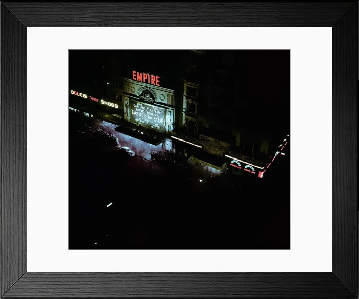 Framed Print : Lights of london. Empire cinema illuminated as crowds queue to watch the film