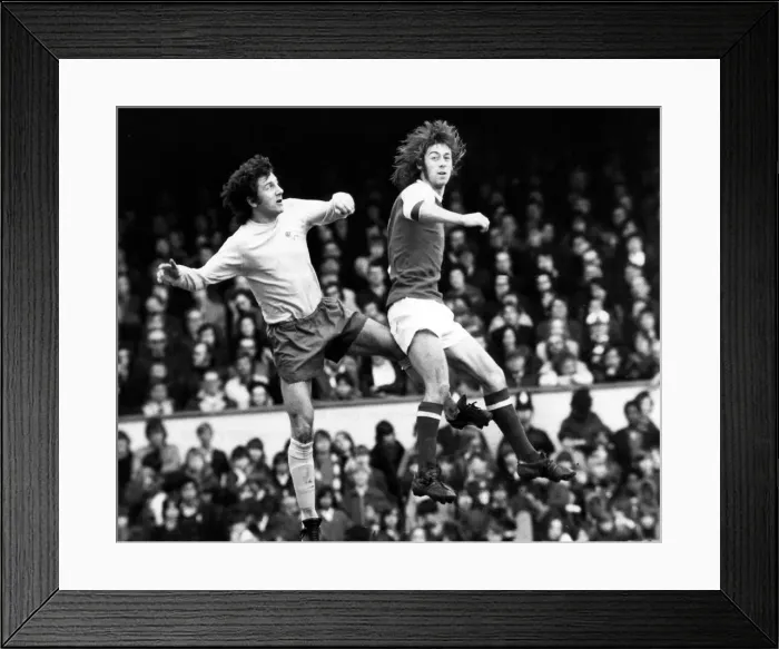 Framed Print : Derby Countys Roy McFarland leaps with Arsenal