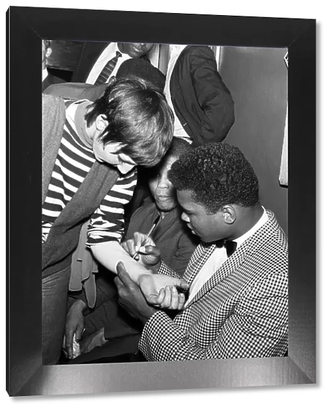 Cassius Clay aka (Muhammad Ali) signs his autograph on a fan