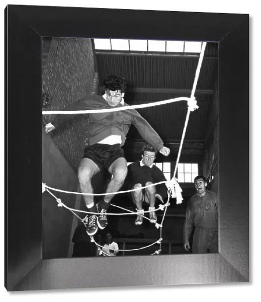 Tottenham Hotspur footballers Ron Henry and Terry Dyson using a rope ladder during a team