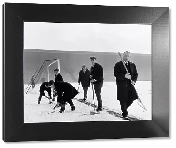 Liverpool manager Bill Shankly helps to clear the snow from the goal line on the Anfield