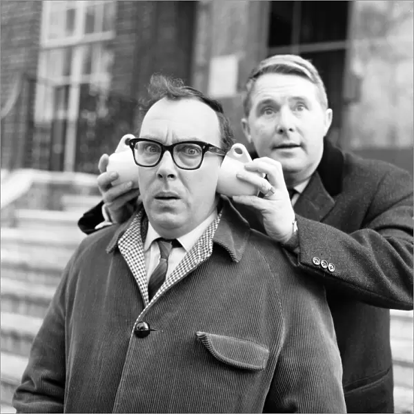 Eric Morecambe gets a new style in ear muffs with coffee cups from his partner