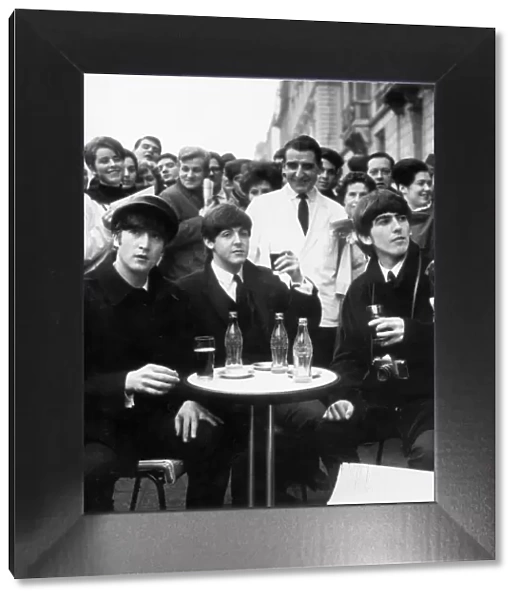 Three Beatles - John, Paul and George enjoy a glass of coca cola at a street cafe in