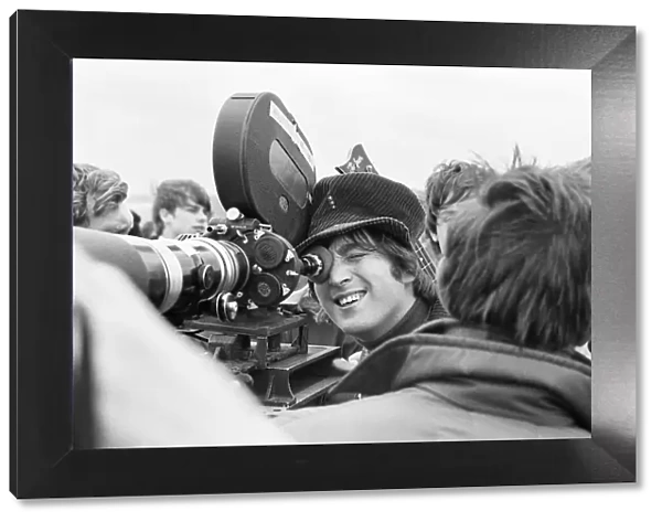 John Lennon of the Beatles pop group, looking through the lens of a camera during