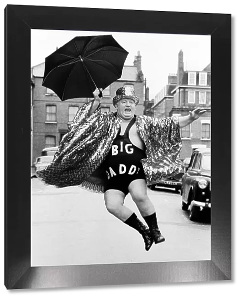 Wrestler Shirley Crabtree alias Big Daddy jumps in the air with an umbrella