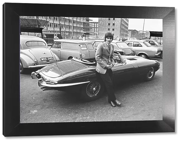 Manchester United footballer George Best with his Jaguar E-Type outside his boutique in