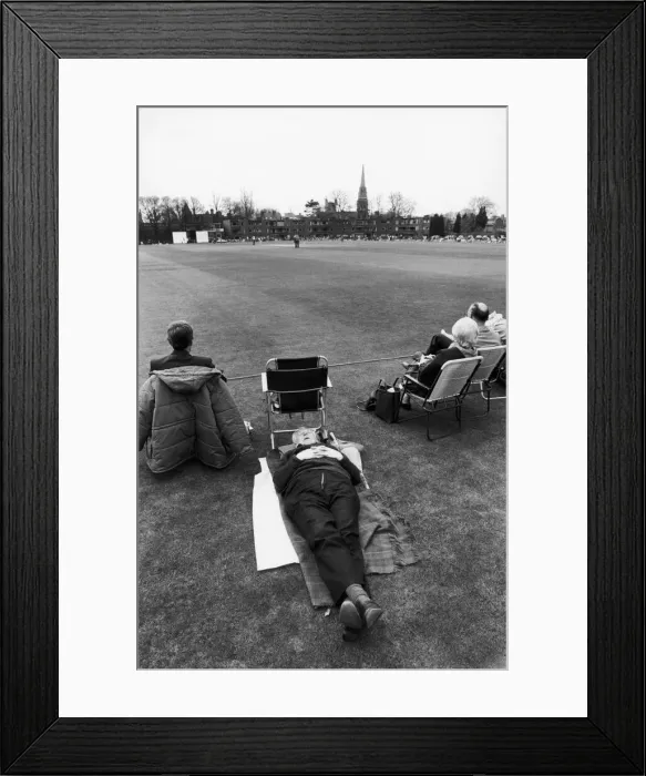 Framed Print : A man falls asleep on the boundary of the first cricket match of the season between Framed Print : A man falls asleep on the boundary of the first cricket match of the season between