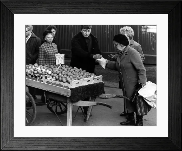 Framed Print : Illegal street trader tommy Quinn makes a sale before having to move on 31st January 1981 Framed Print : Illegal street trader tommy Quinn makes a sale before having to move on 31st January 1981