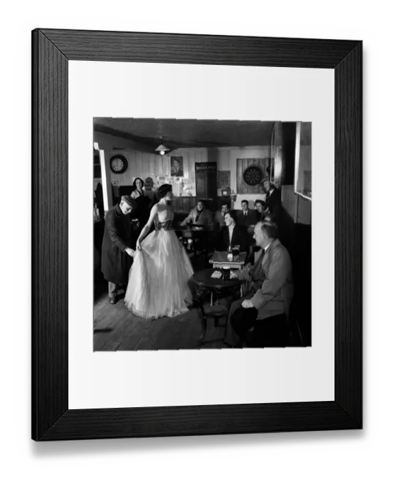 Framed Print : Woman showing off a long white dress to a room full of local men during a fashion Show in Framed Print : Woman showing off a long white dress to a room full of local men during a fashion Show in