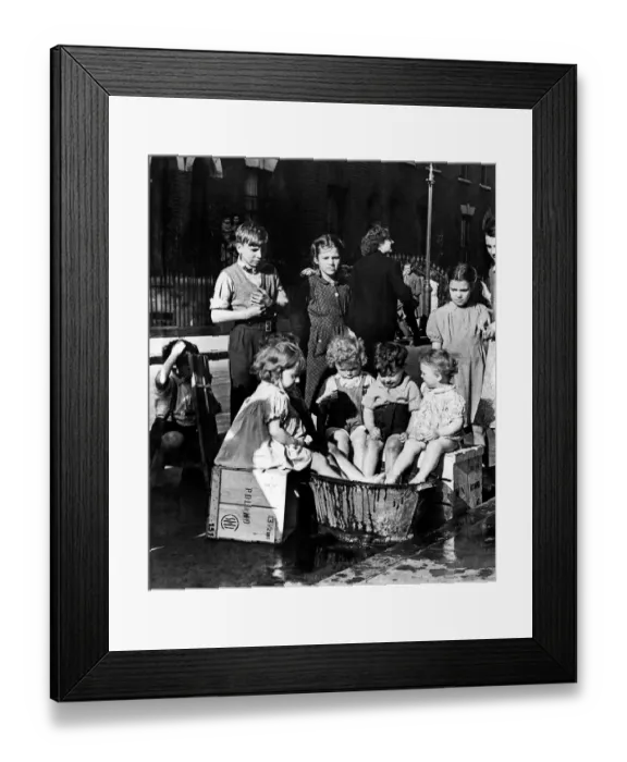 Framed Print : Children in East London take turns to keep cool with a large bucket of water 22nd June
