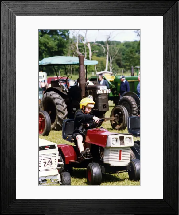 Framed Print : A little boy trying our a miniature tractor on show among the traction engines Framed Print : A little boy trying our a miniature tractor on show among the traction engines