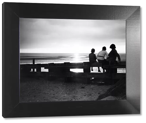 Darkness falls around three children as they watch the sunset at Rye Bay, Sussex