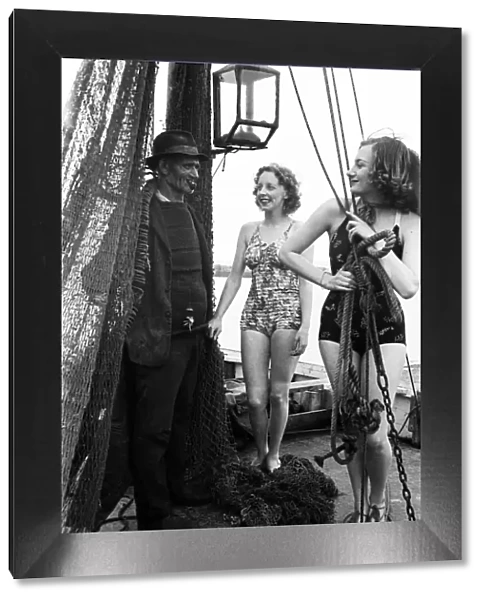 Women in their bathing costumes with a fisherman, along the coast, Hastings, circa 1945