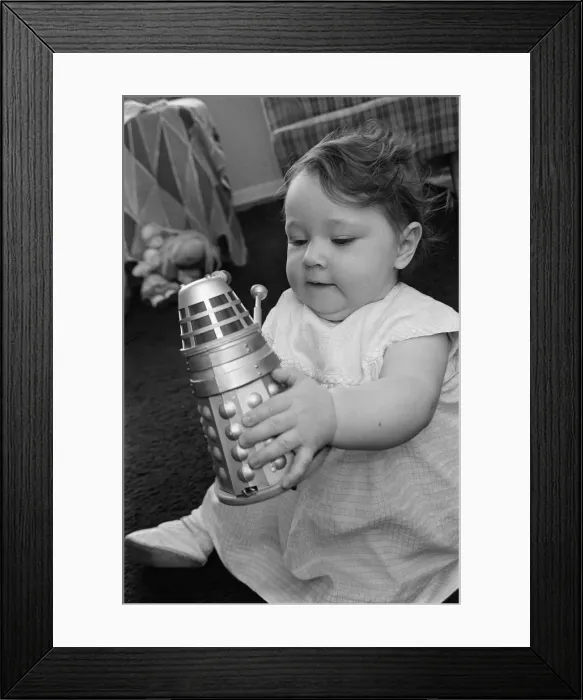 Framed Print : The daughter of Raymond Cusick designer of the Daleks from Doctor Who playing with a toy Framed Print : The daughter of Raymond Cusick designer of the Daleks from Doctor Who playing with a toy