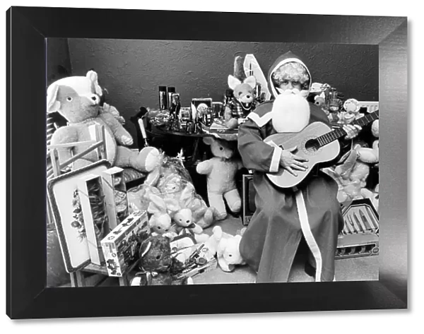 Rod Johnson, a guitar playing Father Christmas, surrounded by toys