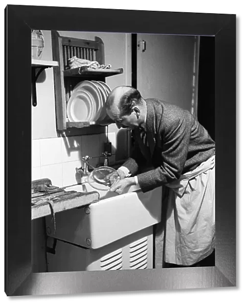 Ted Castle, the husband of Barbara Castle, doing the washing up at the kitchen sink