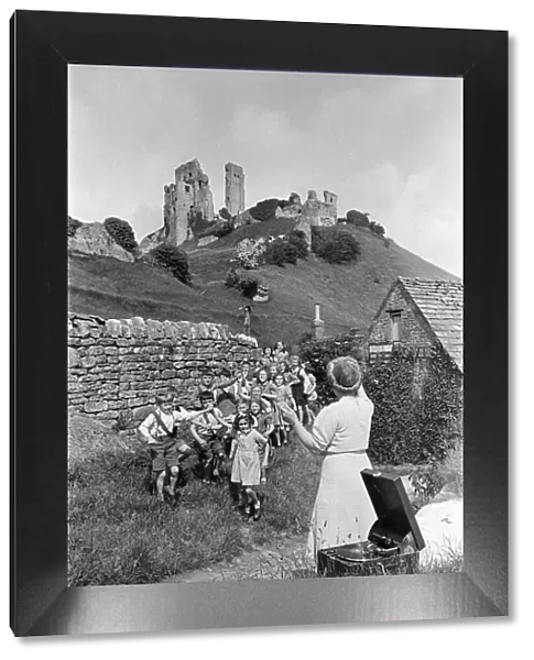 A woman guides a group of children in front of Corfe Castle in Dorset, July 1947