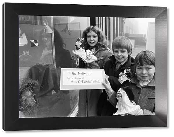 Helme Junior School pupils arranging their Nativity scene in the window of a Meltham