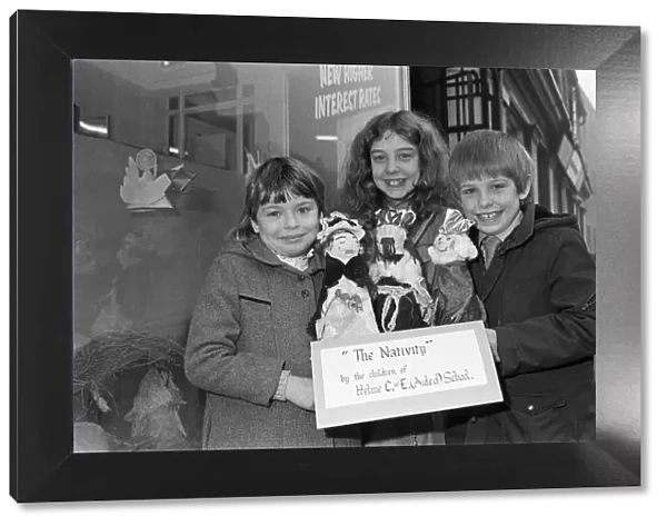 Helme Junior School pupils arranging their Nativity scene in the window of a Meltham