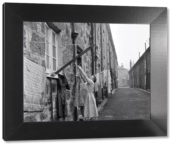 A woman hanging out her washing in a street in St Ives, Cornwall. 15th February 1954