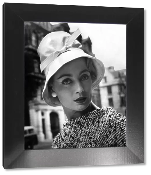 A woman modelling a fashionable hat. July 1957