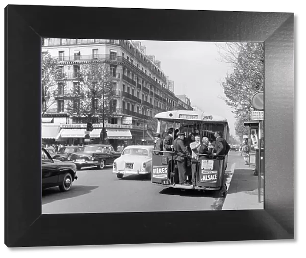 Paris commuters standing on the tail platform of a bus. May 1960