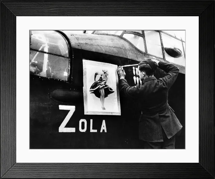 Framed Print : A Lancaster bomber crewman screws on a nose art painting of Zola on to the side of