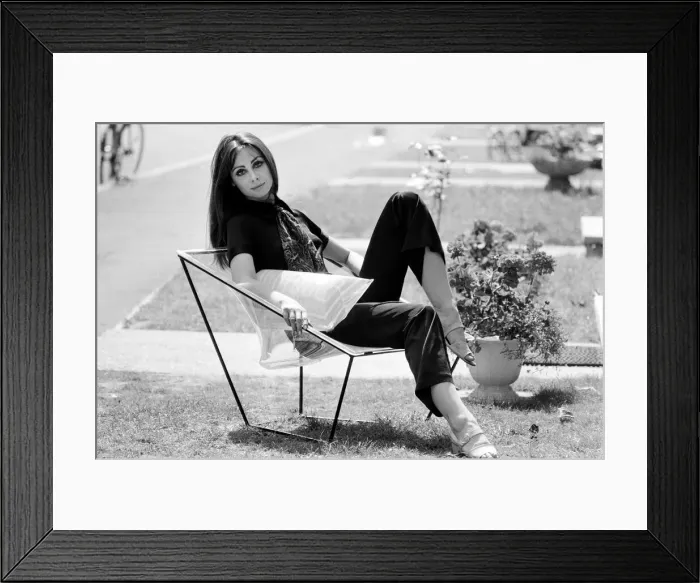 Framed Print : A display of modern furniture, a woman sitting on a transparent chair. 30th June 1969