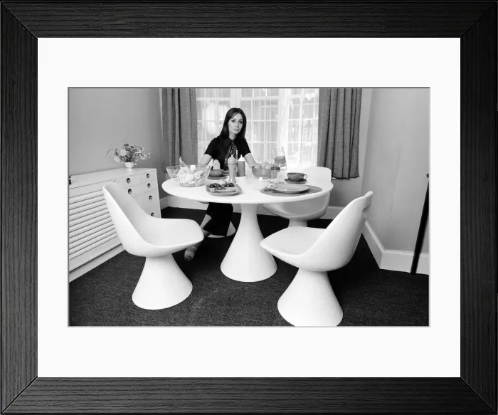Framed Print : A display of modern furniture, a woman sitting in a modern dining room space