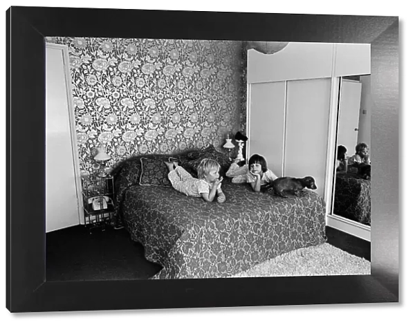 Two children and a dog on a bed in a display of a modern bedroom, 12th May 1969