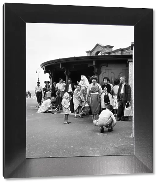 Holidaymakers shelter from the wind on the seafront at Devon. 5th June 1960