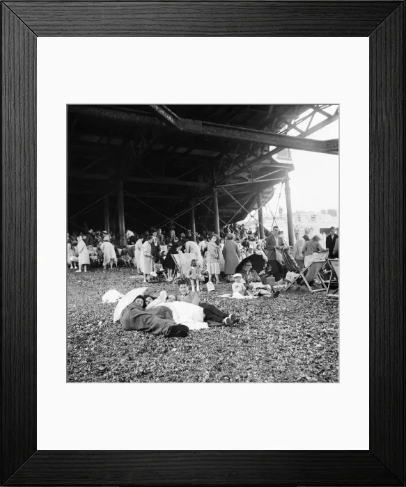 Framed Print : Beach scene Brighton, East Sussex. Crowds seek cover from a summer shower under the pier Framed Print : Beach scene Brighton, East Sussex. Crowds seek cover from a summer shower under the pier