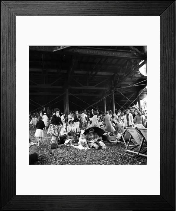 Framed Print : Beach scene Brighton, East Sussex. Crowds seek cover from a summer shower under the pier Framed Print : Beach scene Brighton, East Sussex. Crowds seek cover from a summer shower under the pier