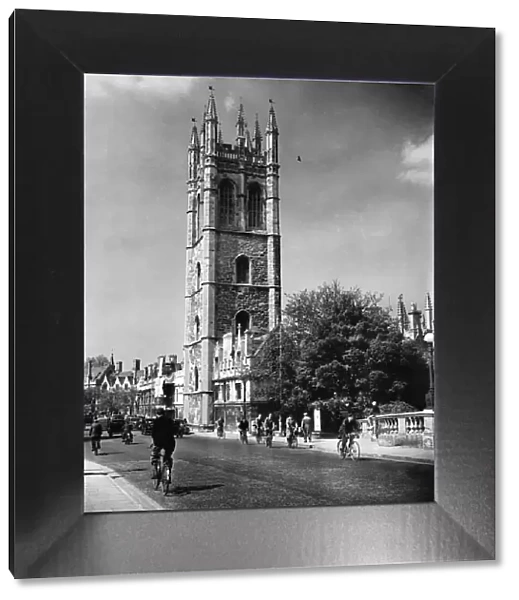 Cyclist in High Street, Oxford, cycling past Magdalen College, Oxfordshire