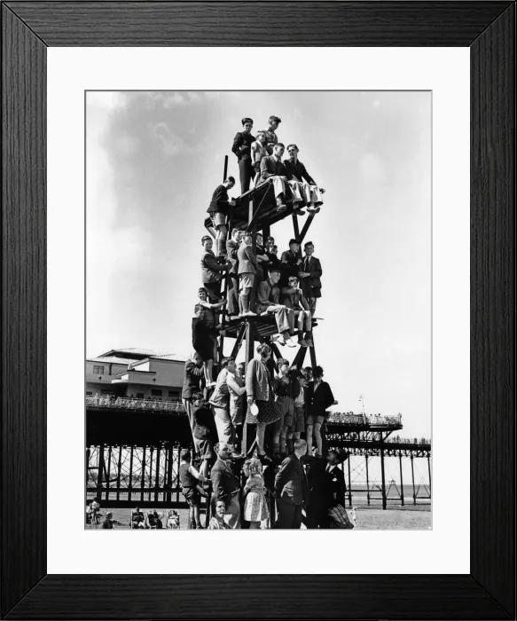 Framed Print : Children make a human pyramid on a lifeguard look-out tower at a Butlins holiday camp Framed Print : Children make a human pyramid on a lifeguard look-out tower at a Butlins holiday camp