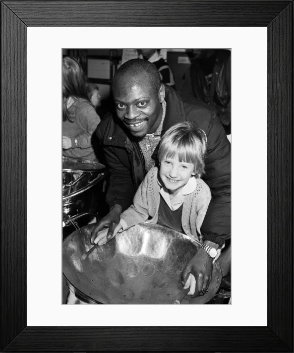 Framed Print : North Star steel drummer Kelvin Benjamin helps Sarah Stead play the soprano drum during Framed Print : North Star steel drummer Kelvin Benjamin helps Sarah Stead play the soprano drum during